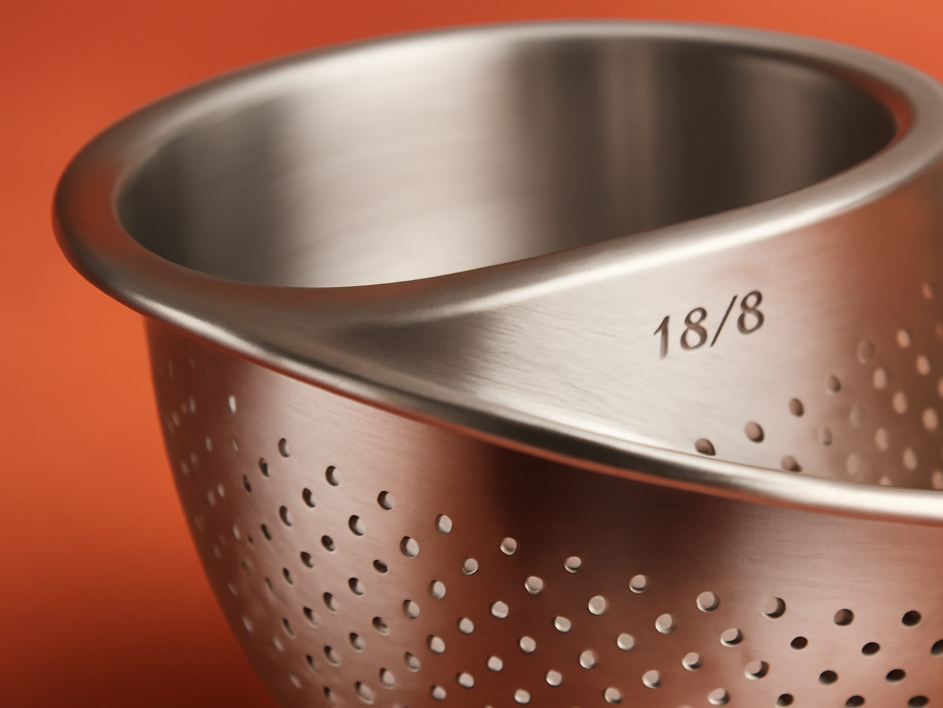 Macro detail of stainless steel colander's perforated holes and polished rim edge